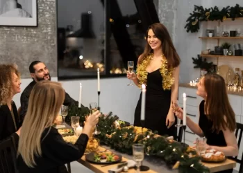 A group of friends enjoying a festive Christmas dinner together, laughing and holding glasses of champagne in a warmly decorated room